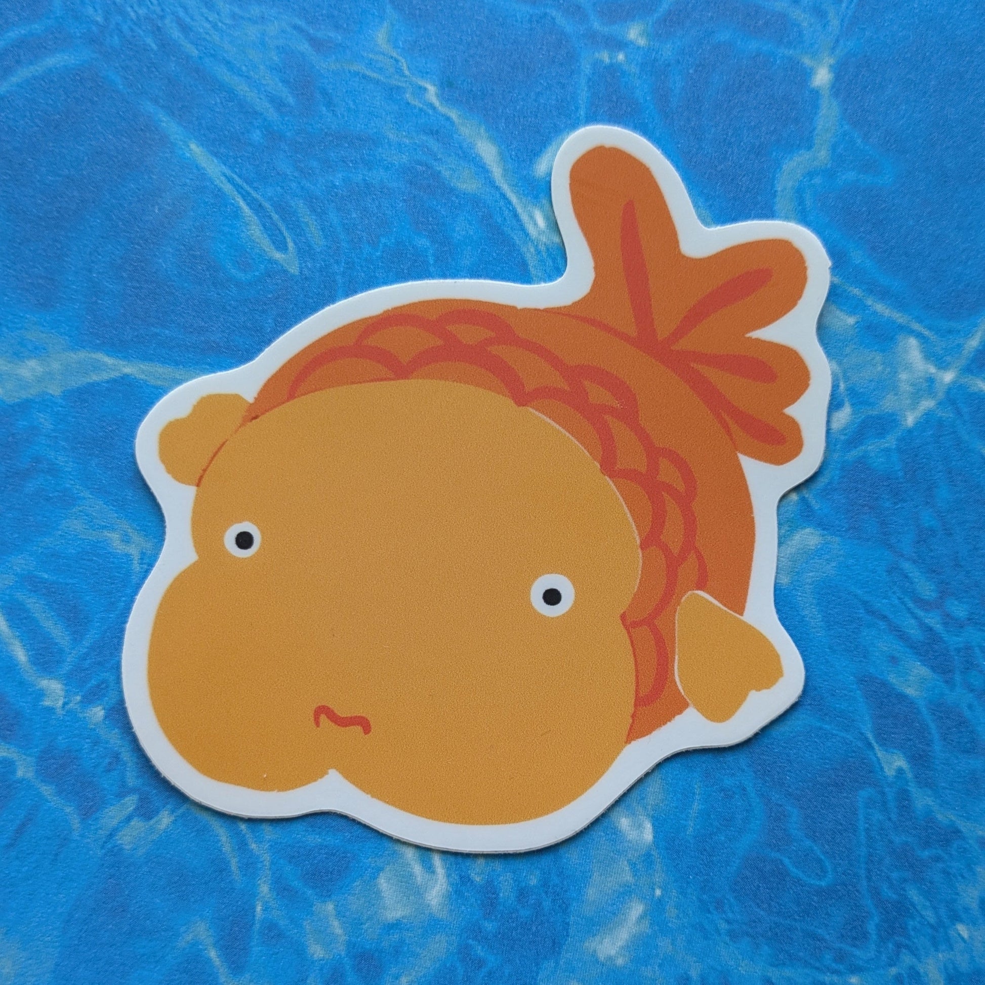 Cartoonish orange fish sticker on a blue textured background