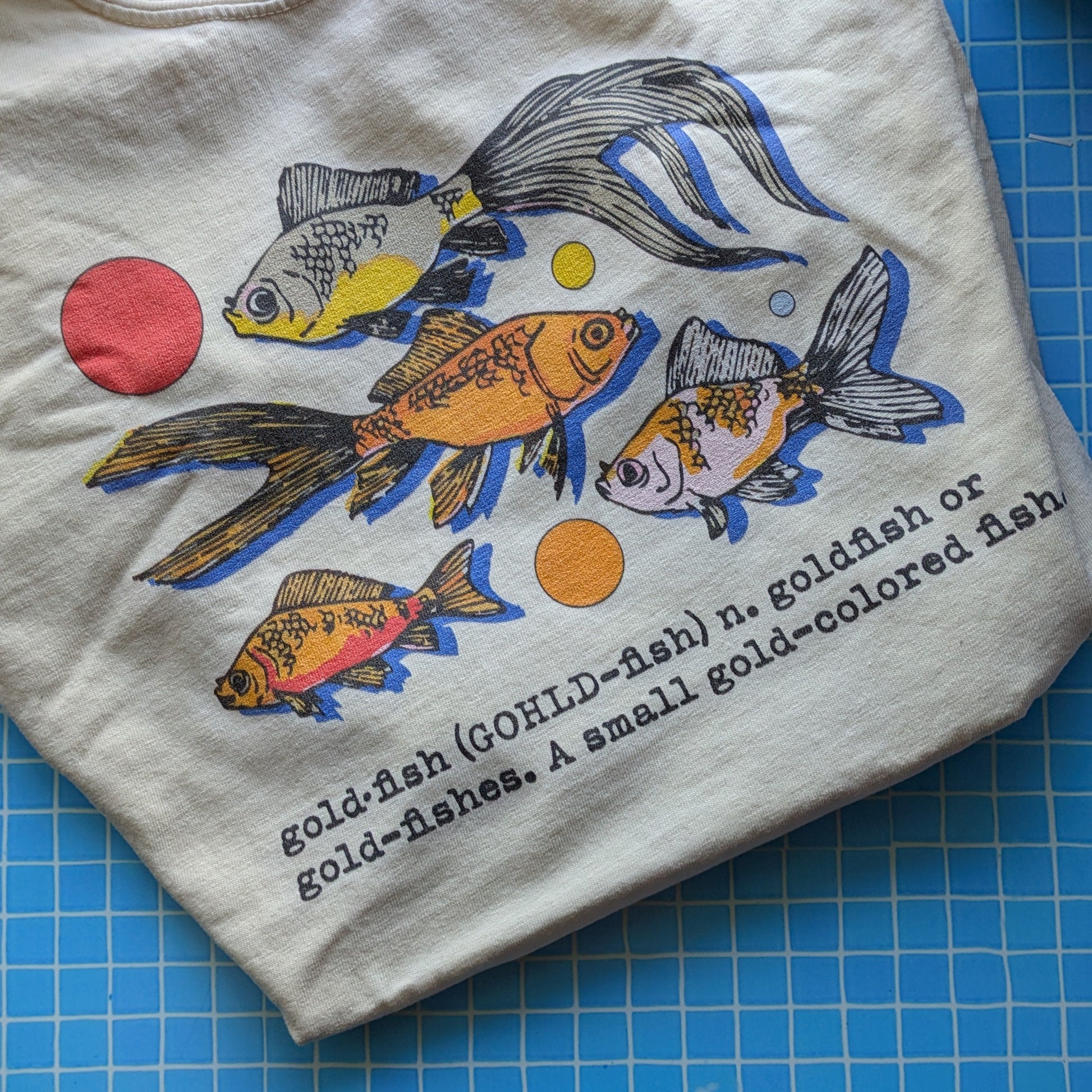 Folded t-shirt with fish illustration on a blue grid surface
