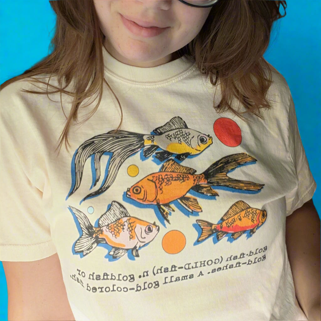 Person wearing a t-shirt with fish designs in front of a blue background
