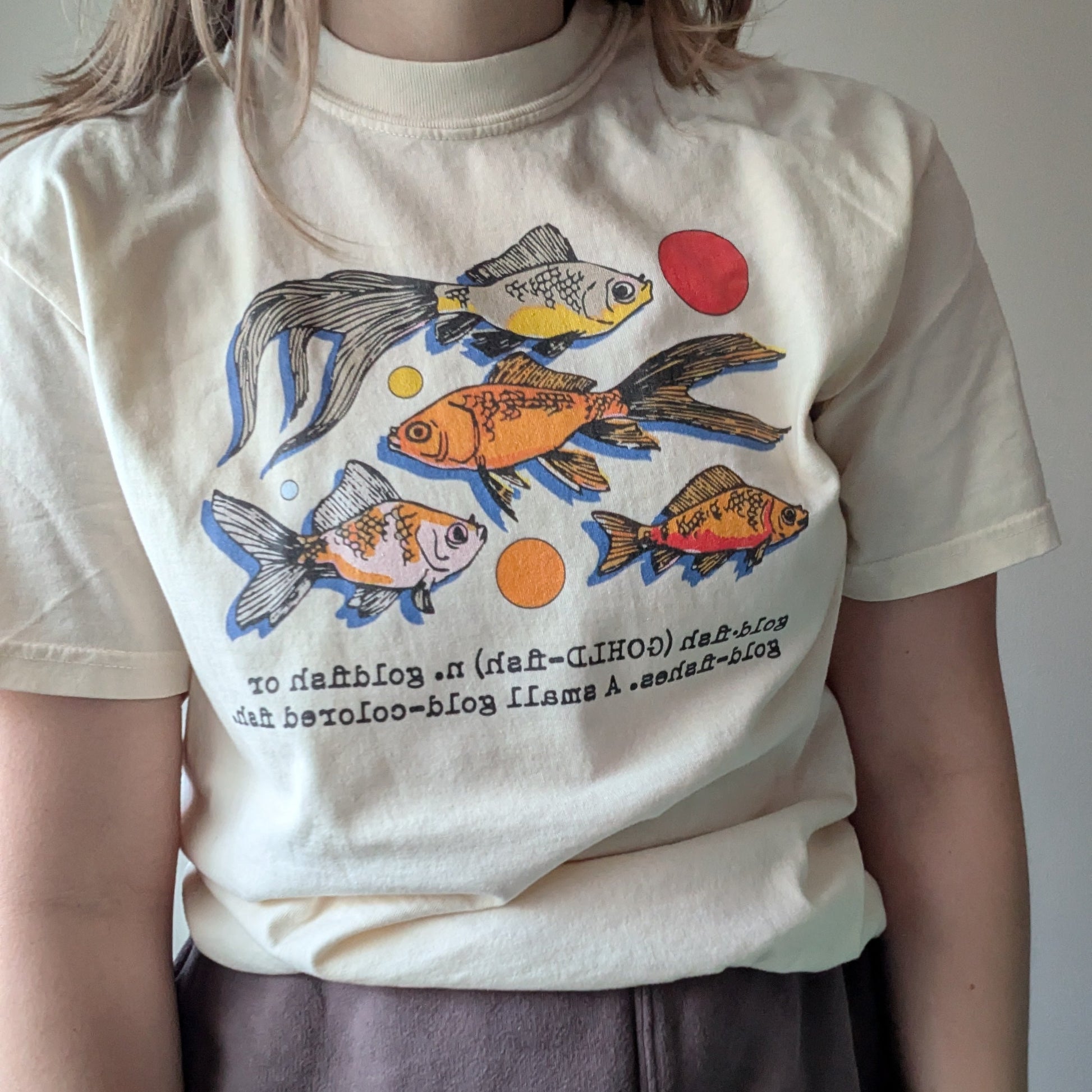 Person wearing a t-shirt with fish graphics and text
